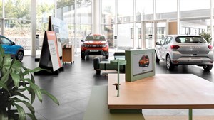 Moder SUV vozila Dacia Bigster vozi po obalni cesti ob vodi. Vozilo je prikazano iz ptičje perspektive, v gibanju.