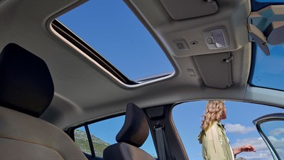 Oranžni Sandero STepway parkiran preh hišo, dekle v ozadju