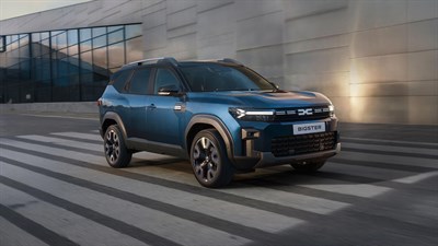 Dacia Bigster vozilo modro sprednji stranski pogled v gibanju pred stavbo