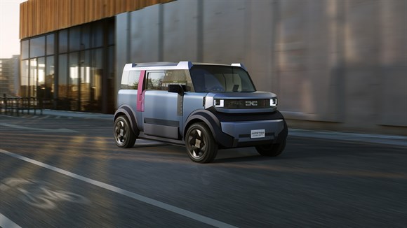 Siv Dacia Duster vozi po gorski cesti ob jezeru.