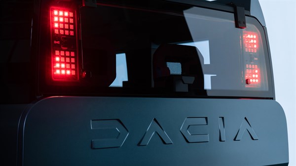 Zadnji del Dacia vozila z rdečimi zadnjimi lučmi in napisom Dacia na vratih prtljažnika.