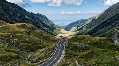 Oranžni Sandero STepway parkiran preh hišo, dekle v ozadju