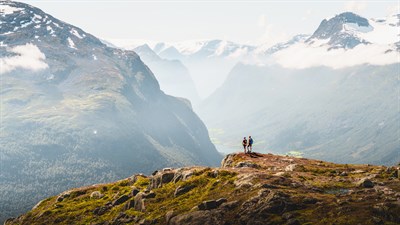 Pohodnika na gorskem grebenu z razgledom na dolino in gore