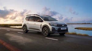 Dacia Jogger sivo sprednji tričetrtinski pogled med vožnjo ob vodi pri sončnem zahodu