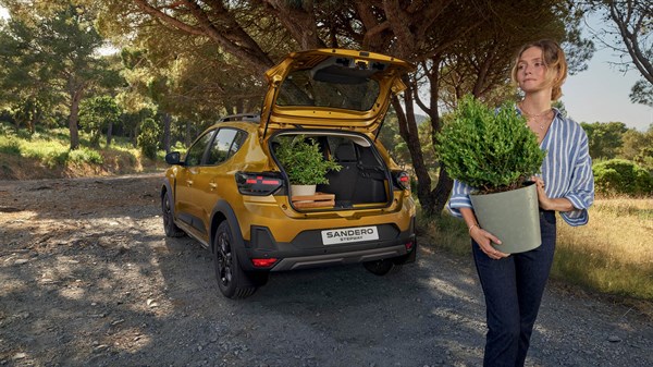 Dacia Sandero Stepway odprt prtljažnik z rastlinami, ženska nosi lonček z rastlino