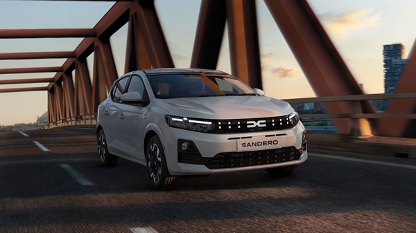 Beli Dacia Sandero sprednji tričetrtinski pogled med vožnjo čez most.
