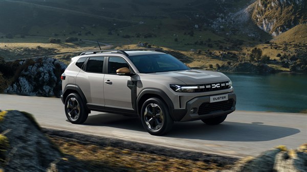 Dacia Duster bež sprednji tričetrtinski pogled med vožnjo v gorski pokrajini ob jezeru