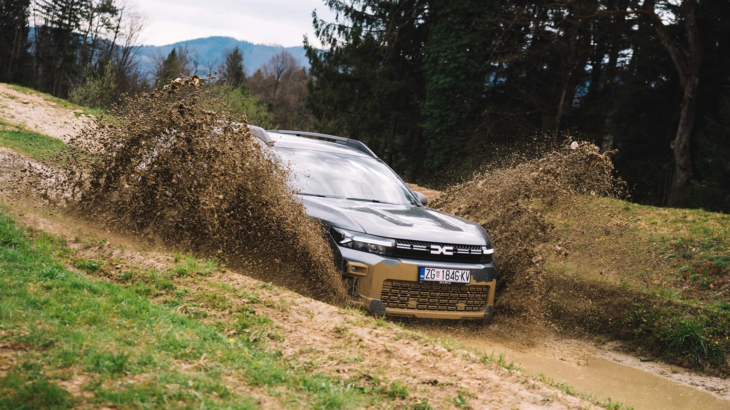 Dacia vozilo vozi skozi blato in ustvarja vodni pljusk na gozdni poti.