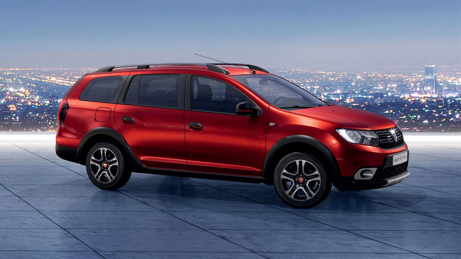 Dacia Logan MCV Stepway rdeča barva, bočni profil s panoramo mesta v ozadju