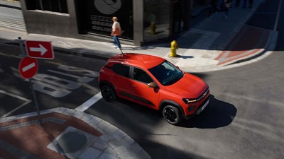 oranžno vozilo Dacia Spring pogled od zgoraj na cestnem križišču