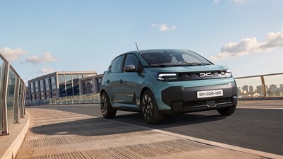Srebrn Dacia Spring med vožnjo po mestni cesti, pogled od zgoraj.