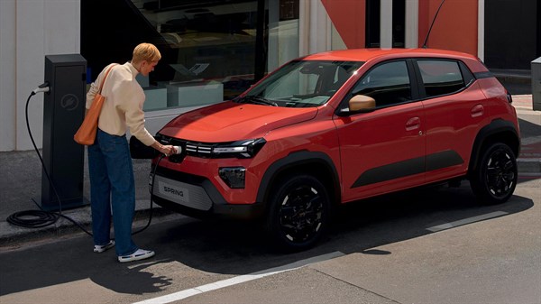 Dacia Spring vozilo oranžno spredaj polnjenje na parkirišču