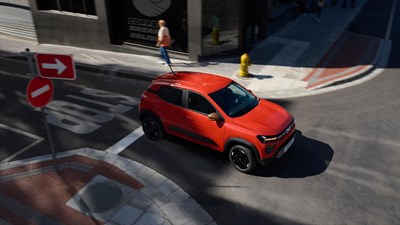 oranžno vozilo Dacia Spring pogled od zgoraj v mestu
