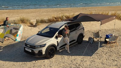 Beli Dacia Jogger bočni profil na plaži s taborom