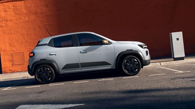 Dacia Spring vozilo belo stranski profil ob polnilni postaji