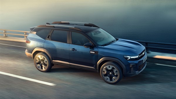 Modri Dacia Bigster bočni profil pri vožnji po avtocesti ob vodi
+