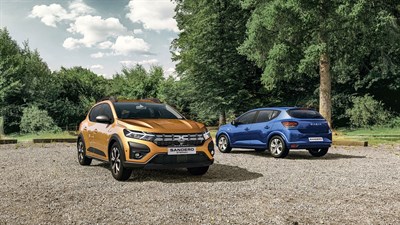 Oranžni Sandero STepway parkiran preh hišo, dekle v ozadju