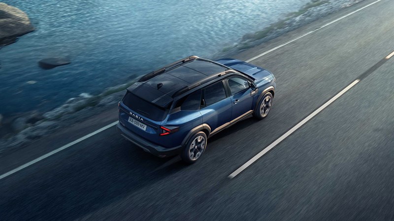 Tri Dacia vozila parkirana na odprtem prostoru, v ozadju morje.