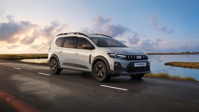 Beli Dacia Jogger med vožnjo ob obali, pogled od zadaj na cesti ob jezeru.