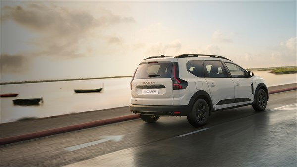 Beli Dacia Jogger med vožnjo ob obali, pogled od zadaj na cesti ob morju.