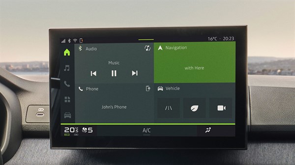 Na sliki je osrednji multimedijski zaslon v vozilu, prikazan v domačem meniju. Zaslon je razdeljen na več razdelkov: zgoraj levo so prikazane možnosti za avdio, vključno z nadzornimi gumbi za predvajanje glasbe.