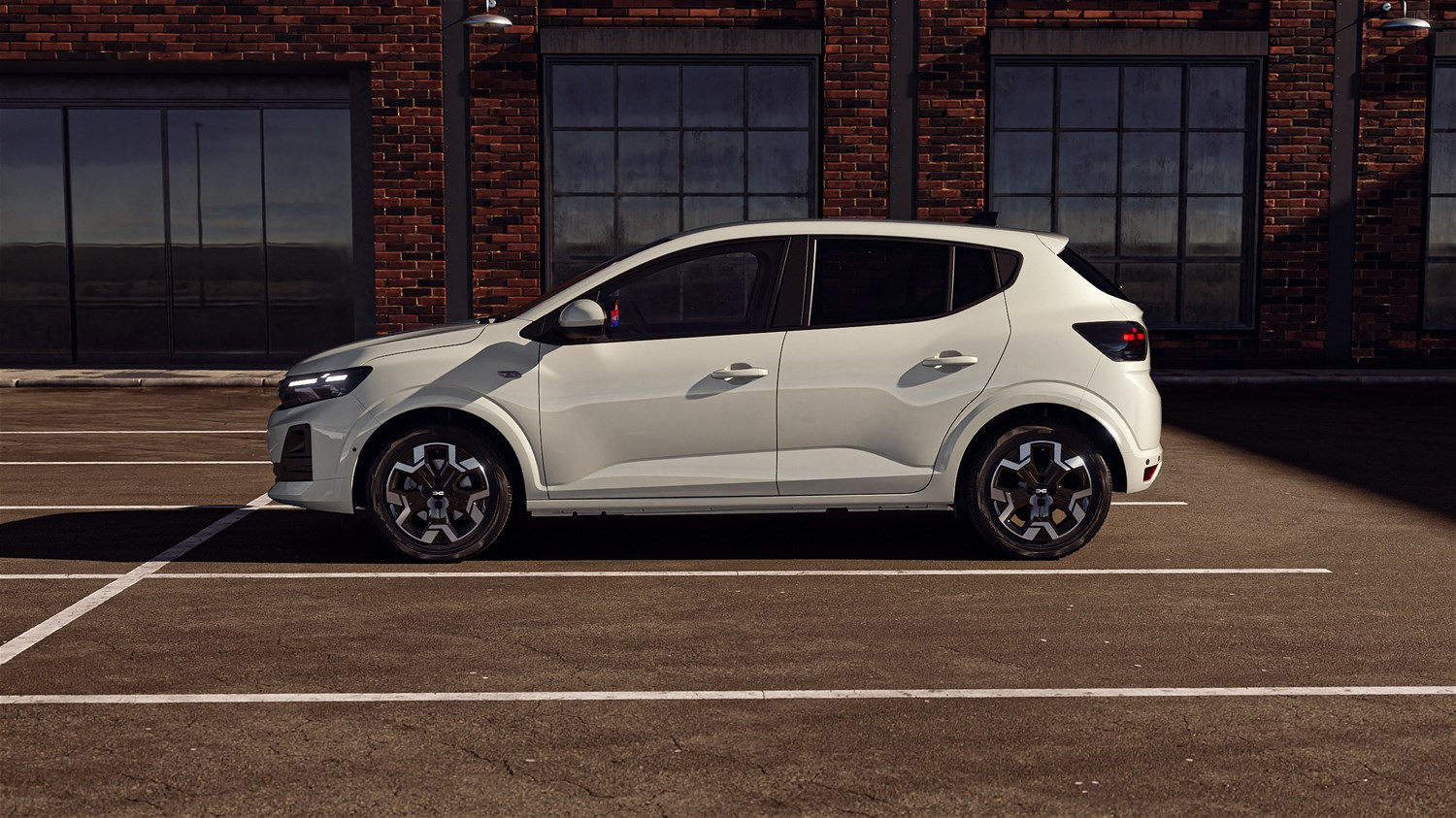 Na sliki je bel mestni avtomobil Dacia Sandero s petimi vrati, prikazan v bočnem pogledu. Parkiran je na praznem, označenem parkirišču.