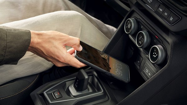 Na sliki je prikazan vgrajeni induktivni brezžični polnilnik za naprave, kot so mobilni telefon in roka, ki mobilni telefon odlaga za polnjenje.