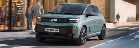 Dacia Spring v svetlo zeleni barvi med vožnjo po mestni ulici