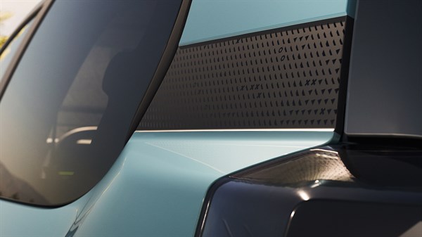 Dacia Spring v svetlo zeleni barvi, parkiran pred sodobno industrijsko stavbo