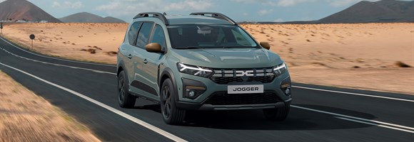 Sivi Dacia Jogger vozi po asfaltni cesti skozi puščavsko pokrajino.